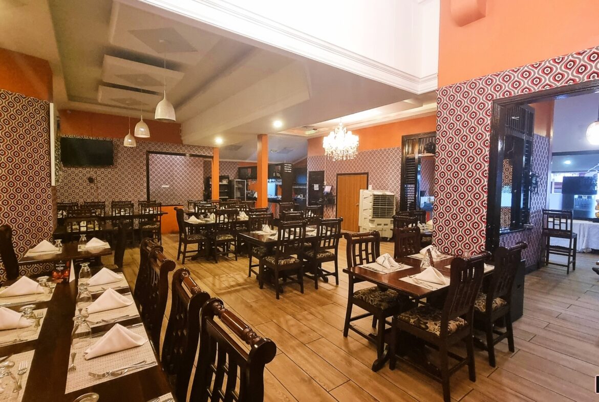 Bright orange restaurant interior with tables, chairs, and a chandelier. "Prime Restaurant Space"