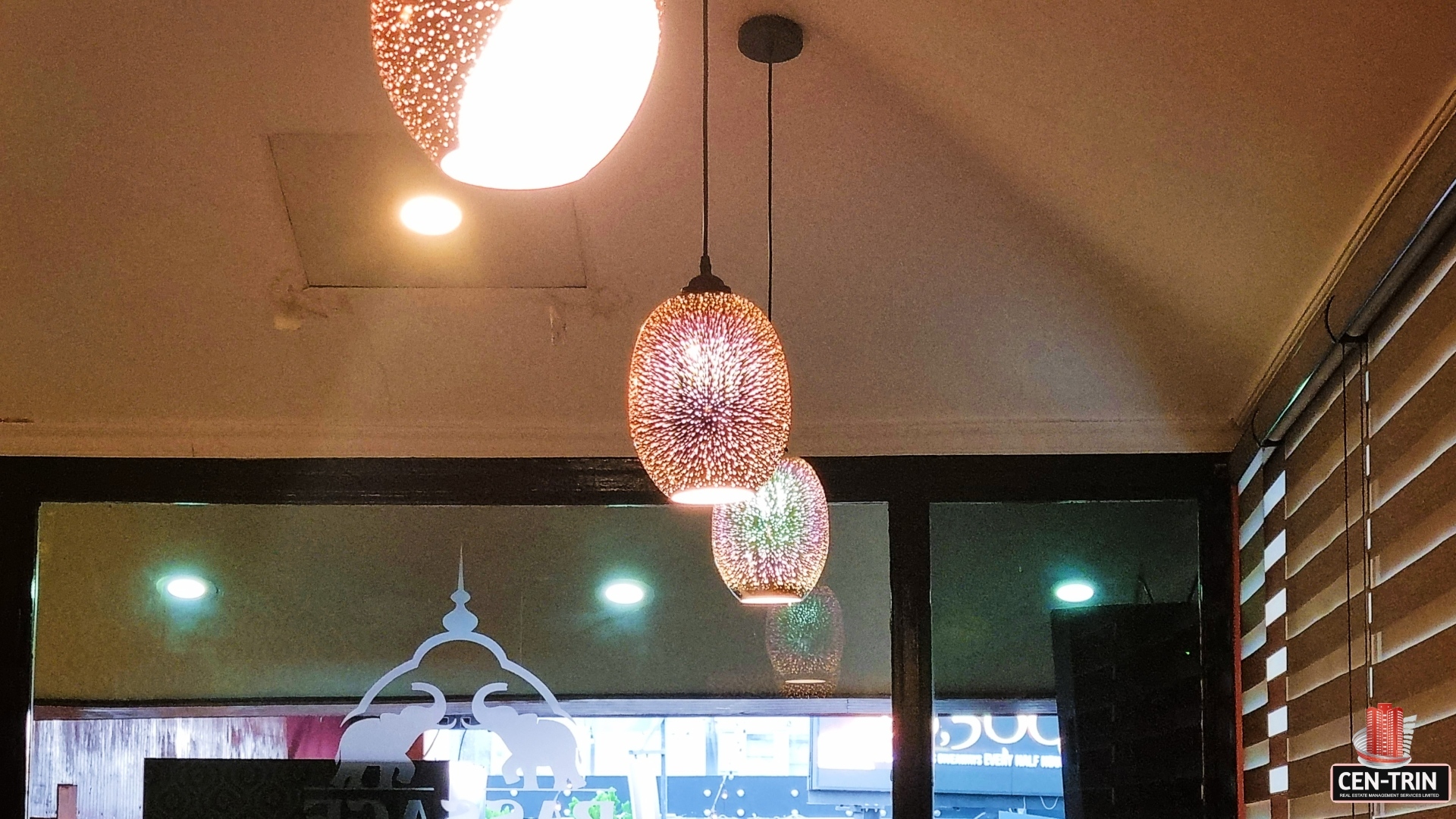 Three pendant lights with colorful glass shades hanging from a white ceiling. "Prime Restaurant Space"