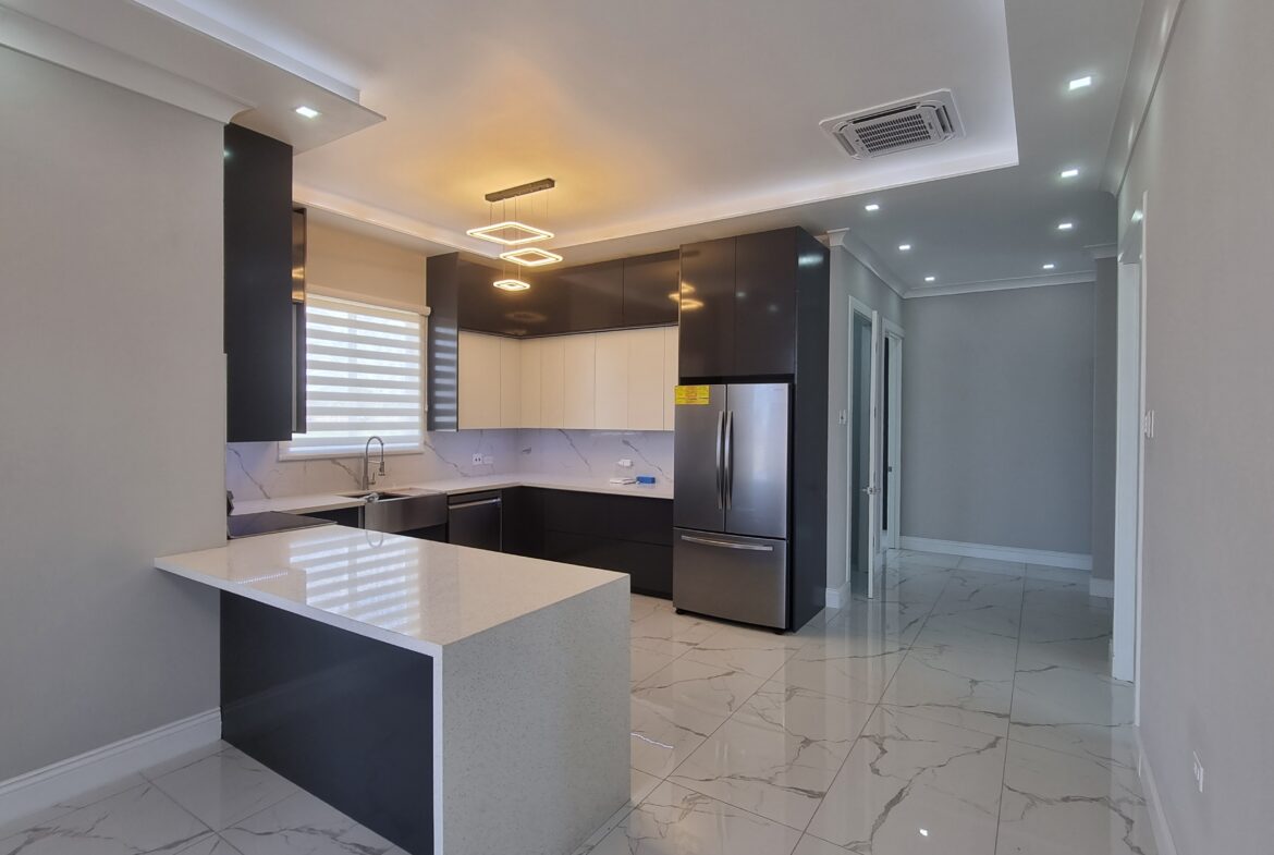 Modern kitchen with white and dark wood cabinets, stainless steel appliances, and breakfast bar in a Freeport home.