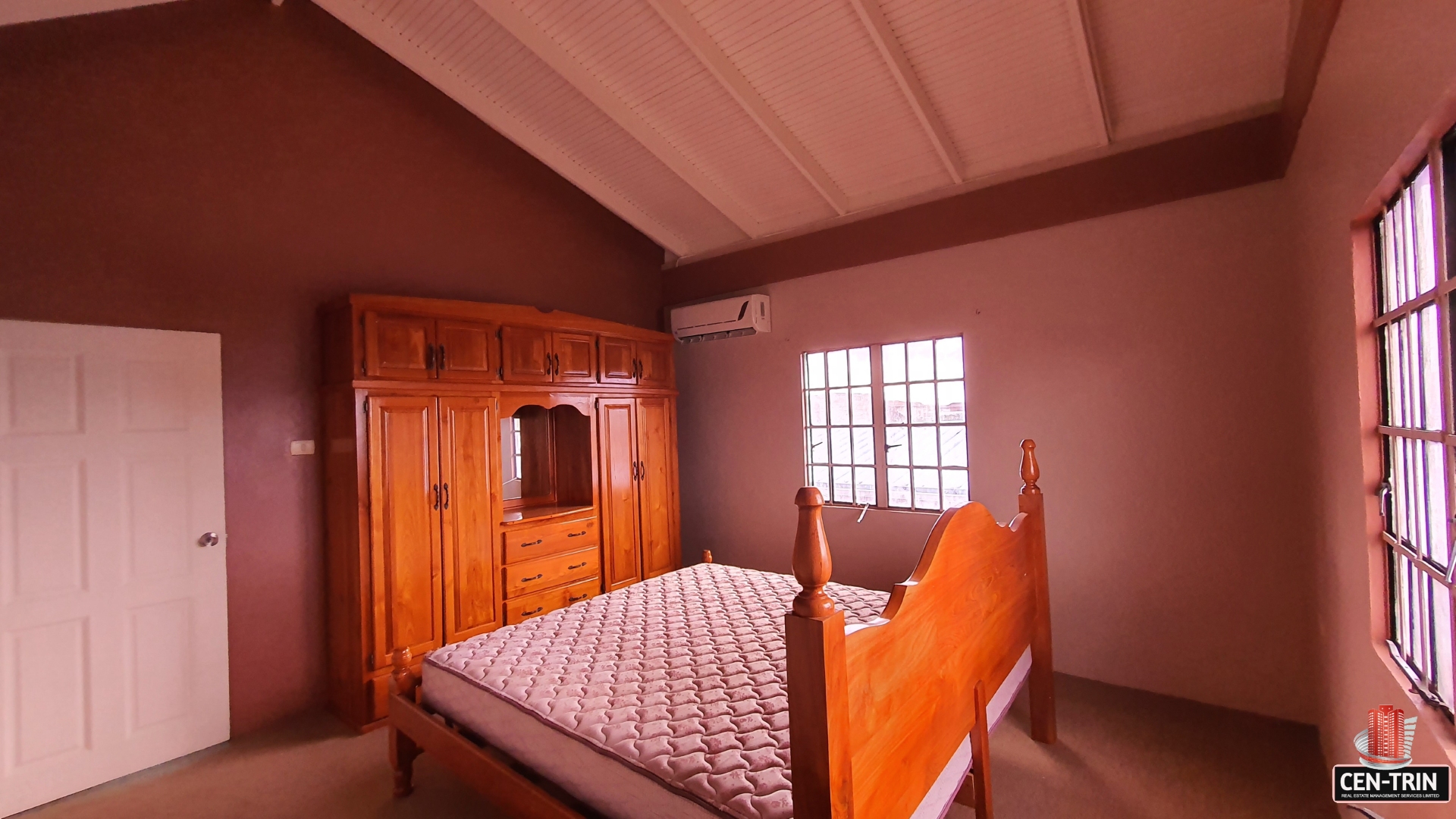 A charming bedroom with a wooden bed frame, wardrobe, and a mirror.