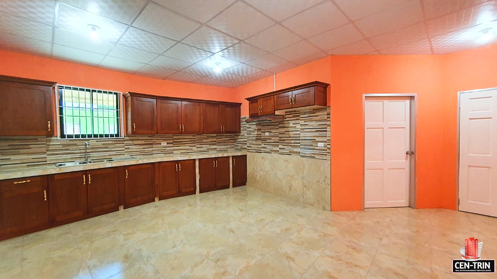Kitchen with stainless steel sink and faucet, wooden cabinets, and orange walls in this 2-Bedroom Apartment for Rent