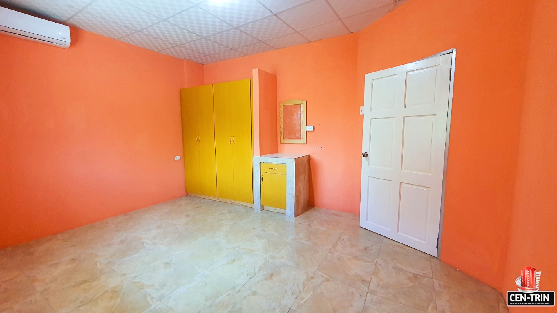 Bedroom interior with orange walls, a white wardrobe with mirrored doors, and a closed white door.
