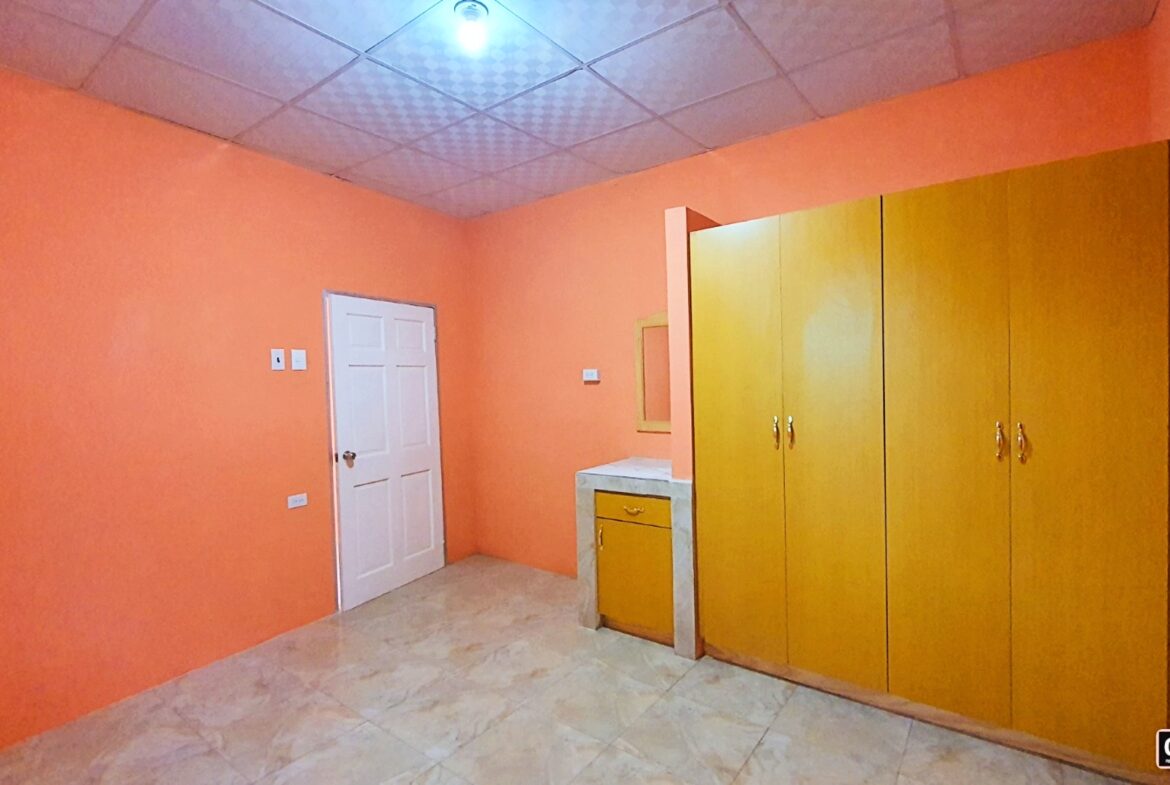 Interior of a bedroom with orange walls and wooden cabinets.