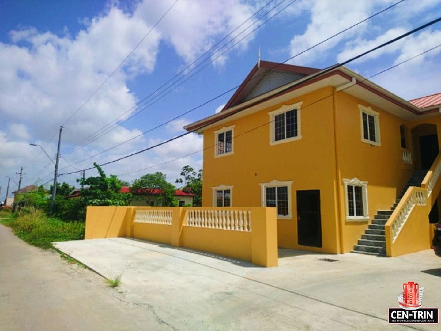 Affordable 2 Bedroom Apartments | A yellow two-story apartment building with stairs leading up to the first floor. There is a sign out front that says "For Rent." The building is located in a rural area with trees in the background.