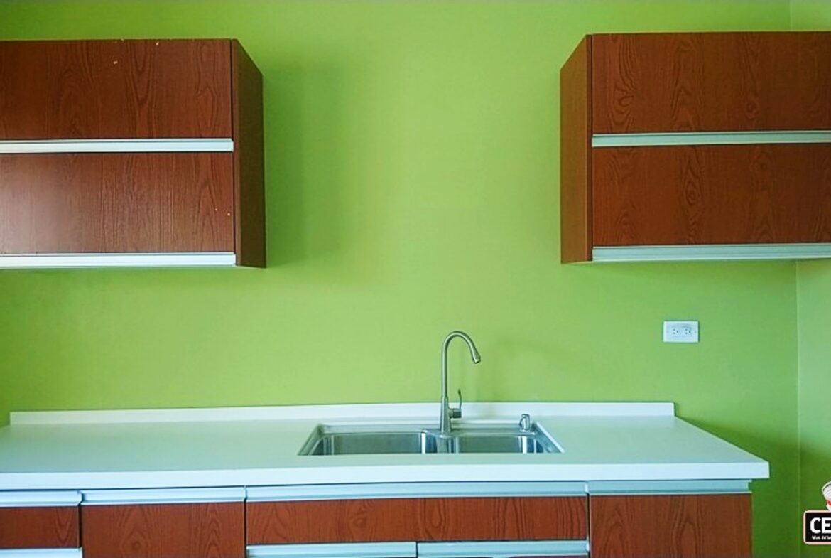 Gated Compound Apartments Cunupia | A bright kitchen with green walls and white countertops in a two-bedroom apartment