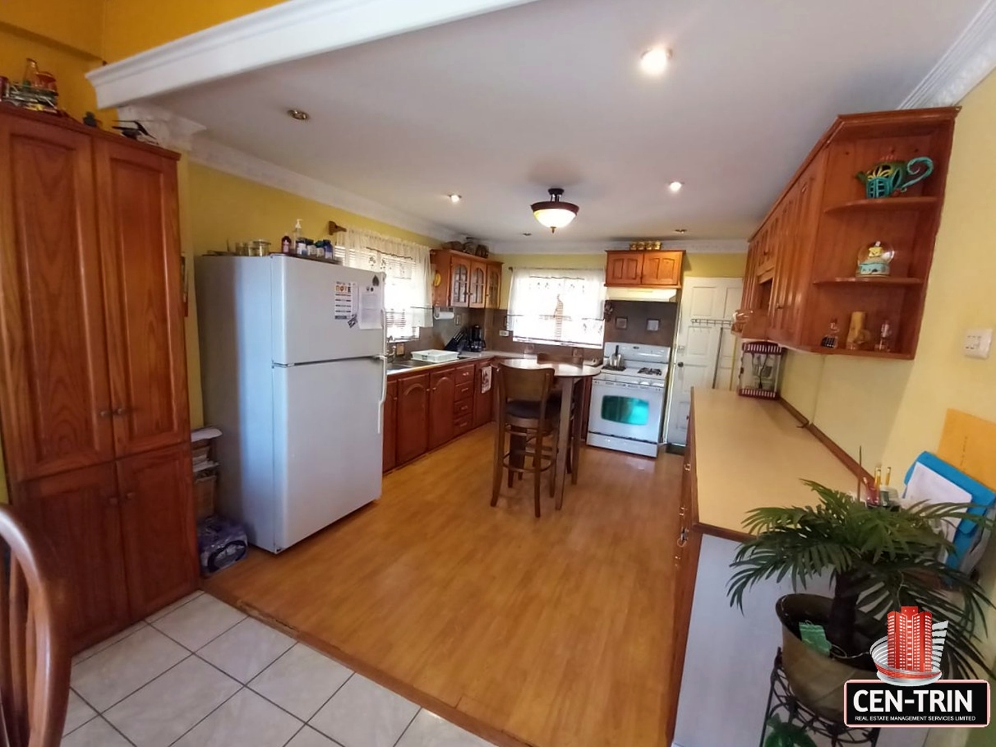 A kitchen with a refrigerator, stove, and table in a 3-bedroom house for sale.
