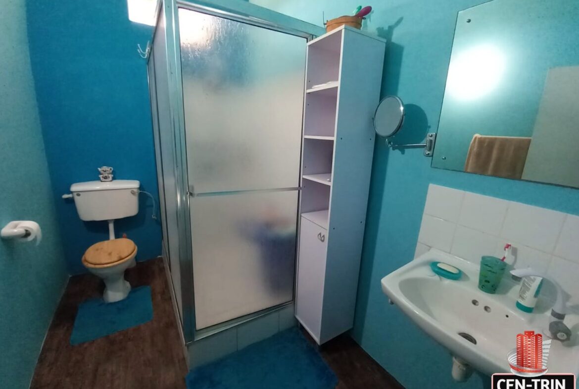 A bathroom with a toilet, sink with faucet, and a shower with a glass door.