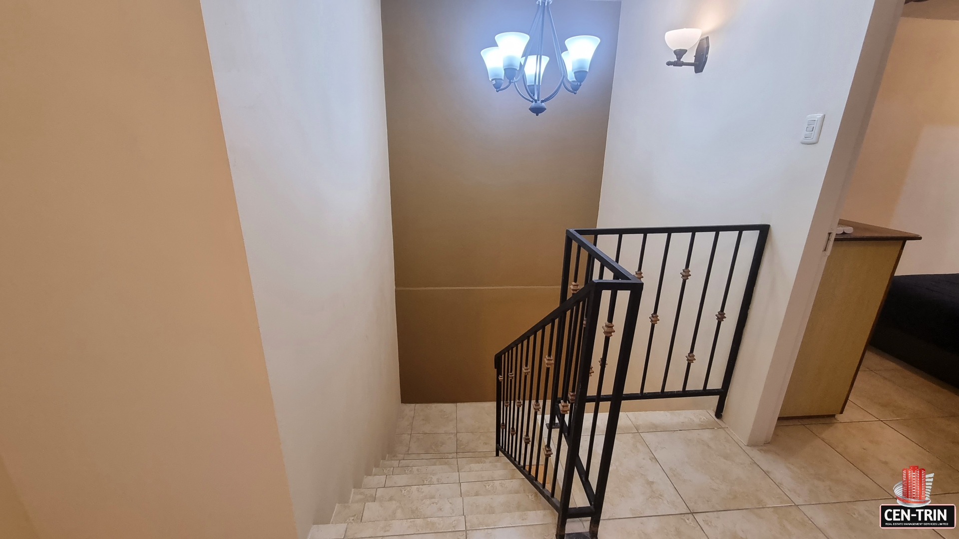 Staircase with wrought iron railing and chandelier in townhouse for sale.