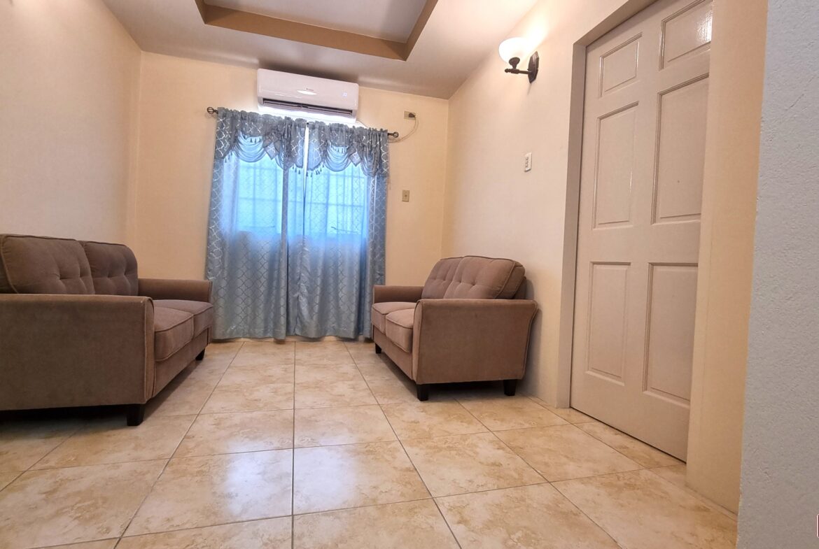 Upper sitting area in townhouse for sale with two couches, a window, and a door.