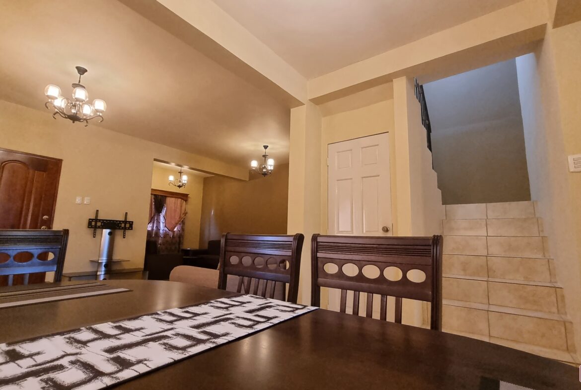 Dining room area in townhouse for sale with table and chairs in front of a staircase