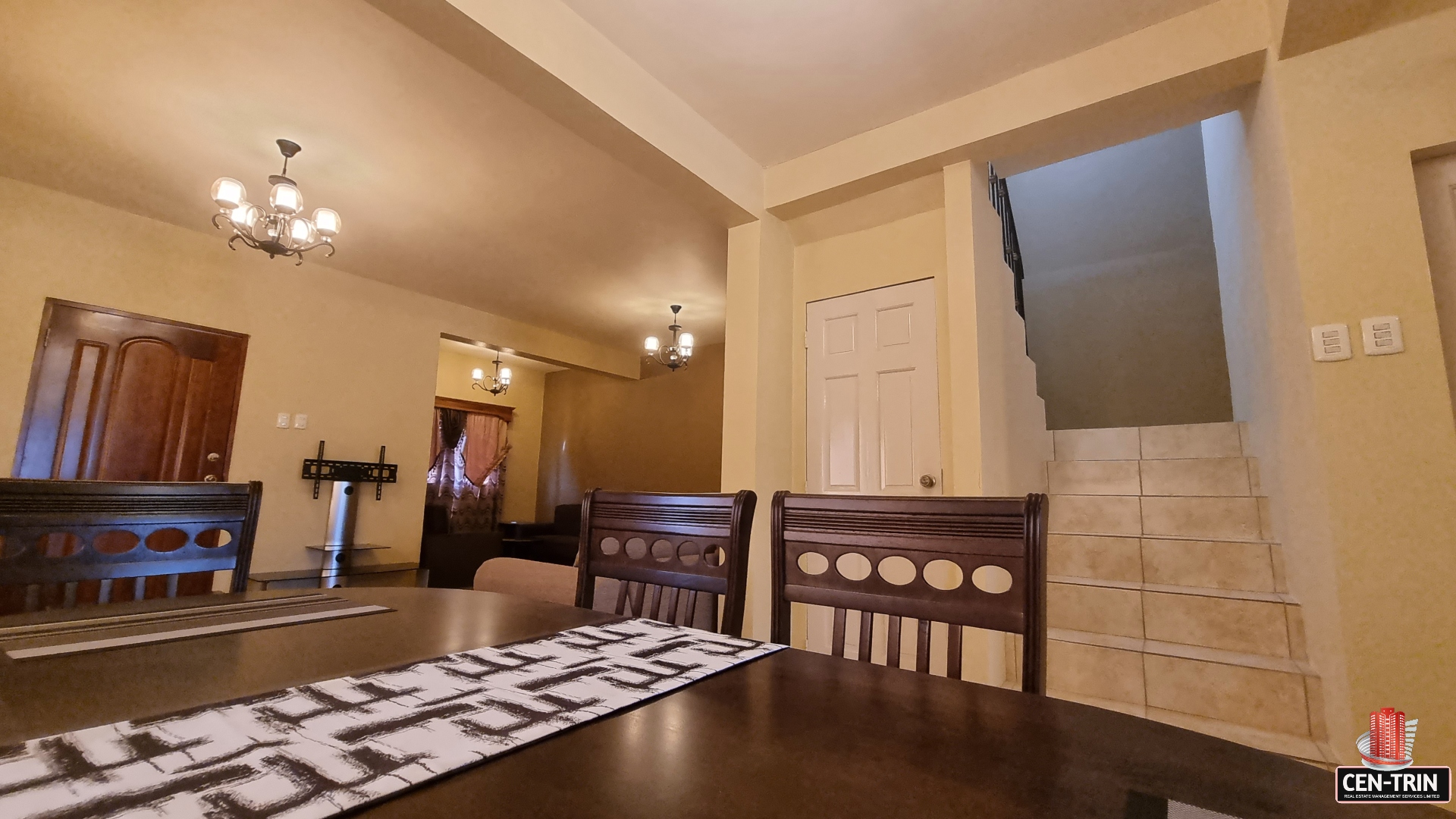 Dining room area in townhouse for sale with table and chairs in front of a staircase