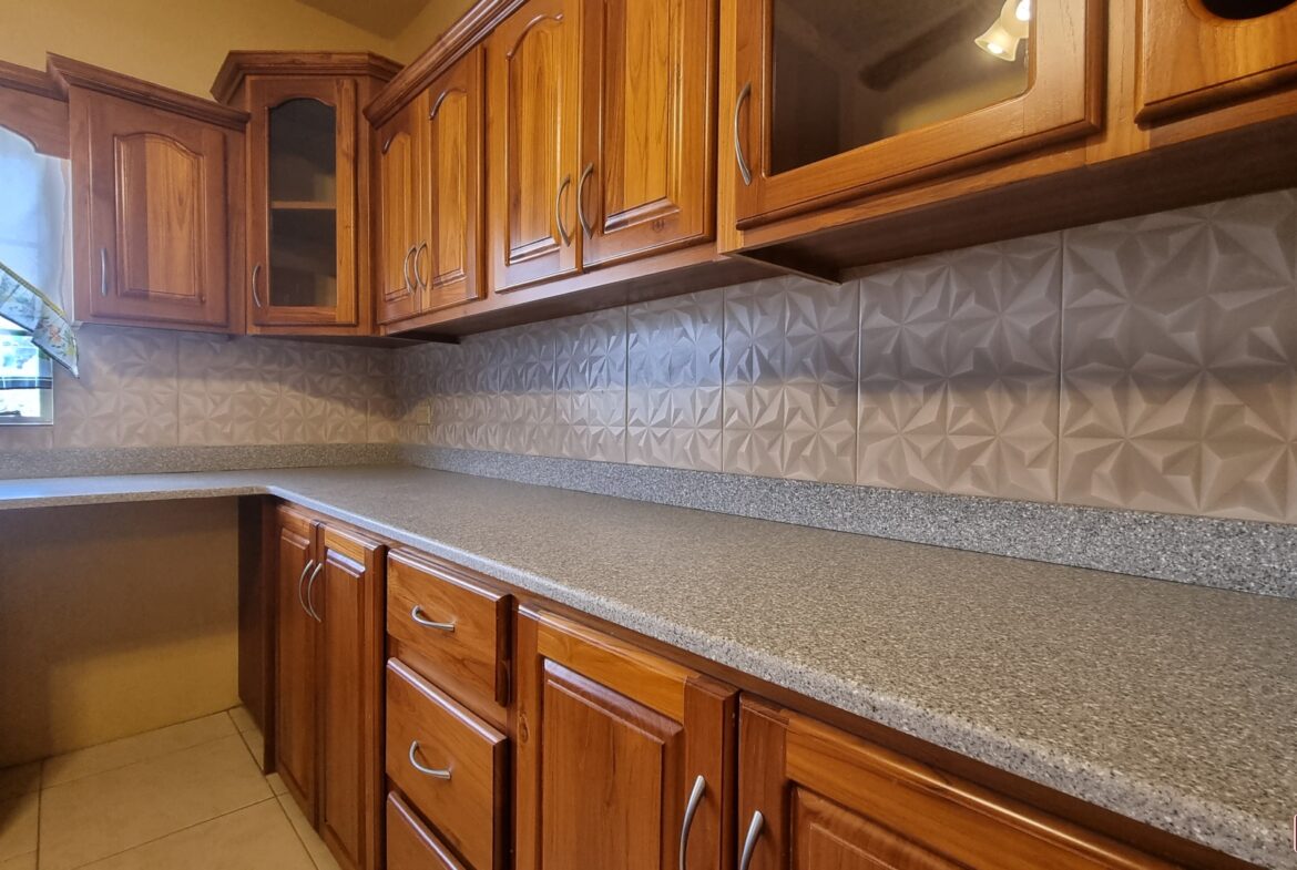 Kitchen counter with gray countertops and stainless steel sink in townhouse for sale.