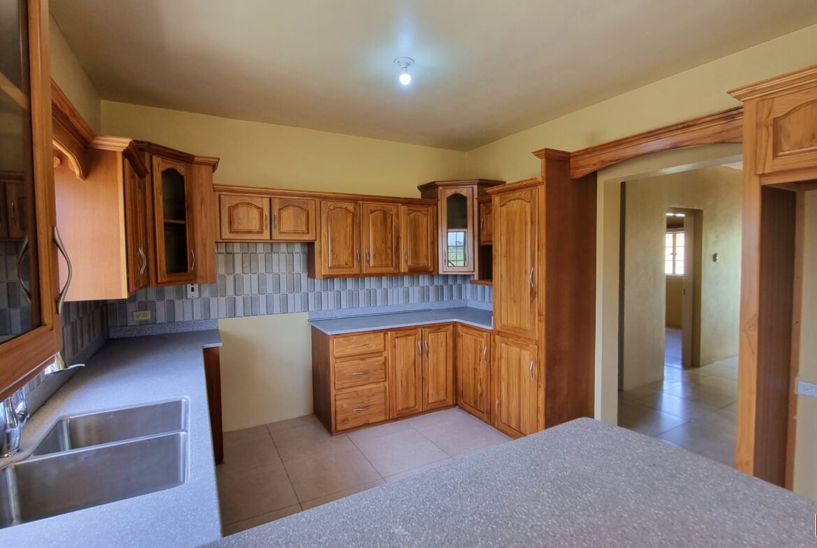 Kitchen with wooden cabinets, double sink, faucet, and granite countertops in townhouse for sale.