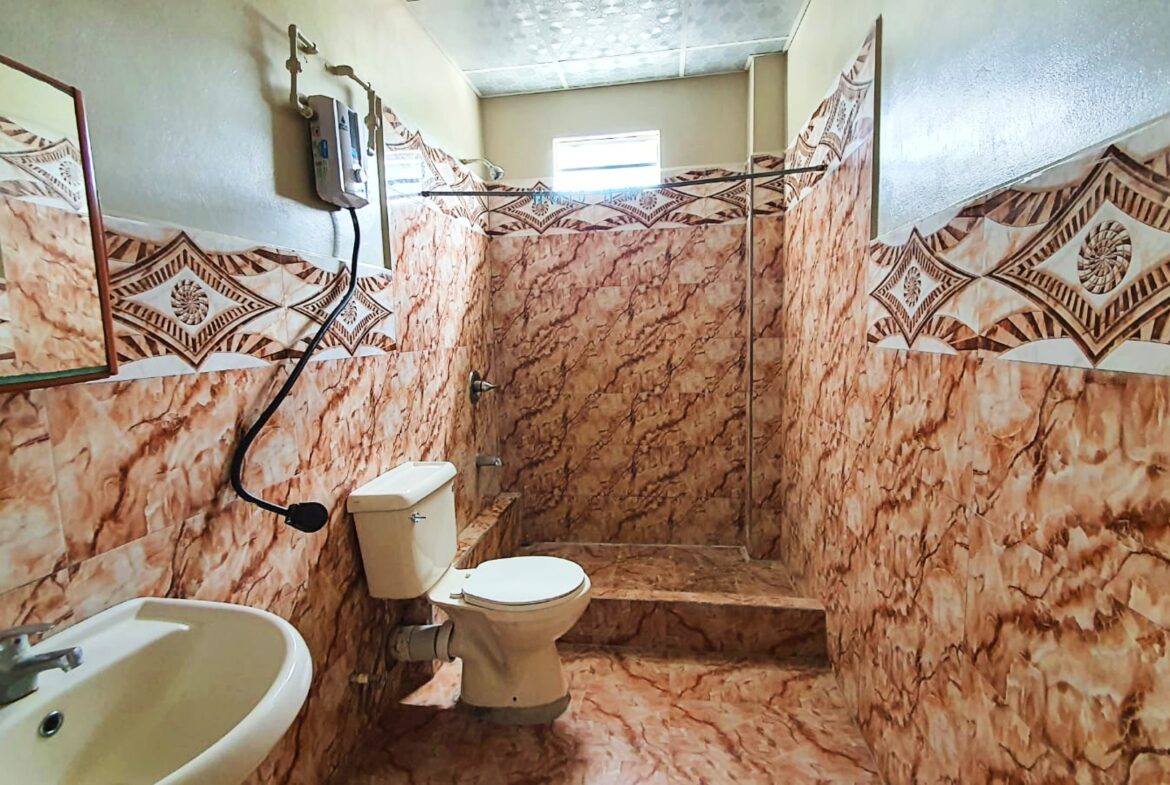 Bathroom with toilet, sink, and shower with enclosure.