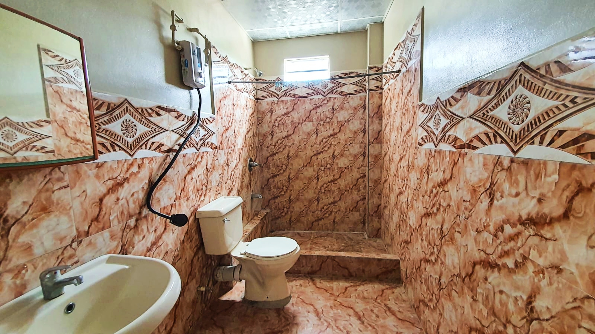 Bathroom with toilet, sink, and shower with enclosure.