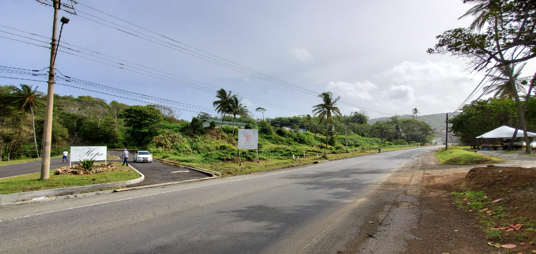 The entrance to Hope Estate, Tobago, with a prominent sign and a well-maintained road leading to the community.